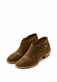 Botas de tobillo de ante marrón con un bajo tacón de madera. Costura decorativa en un patrón de diamante en la puntera. Detalle de hebilla en el lateral.