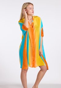 Lichtgewicht, veelkleurige shirtjurk met oranje, gele en blauwe tinten; heeft een knoopsluiting aan de voorkant en mouwen tot de elleboog.