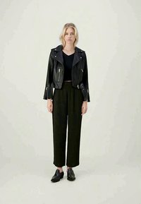 Μαύρο δερμάτινο μπουφάν μοτοσικλέτας με ασημί φερμουάρ, μαύρο V-neck τοπ, αέρινες μ�αύρες παντελόνες και μαύρα λουράκια παπούτσια. Λείος υφάσματος και εφαρμοστό σχέδιο.