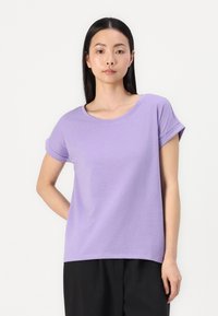 Violet īsām piedurknēm T-kreklis, kas izgatavots no mīksta kokvilnas; tam ir apaļa kakla izgriezuma forma un rullētas piedurknes, kā arī brīva piegriezuma forma. Vienkārša, vienkrāsaina.