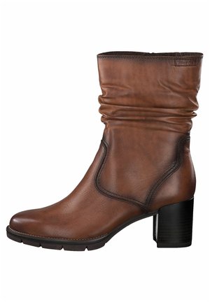 Bottine en cuir marron avec un talon bloc de 5 cm, bout rond et détail de tige plissée douce sur fond blanc.