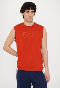 Rdeča brezrokavna majica iz mehkega materiala, z embosiranim logotipom EA7 Emporio Armani na sprednji strani, z sproščenim krojem.