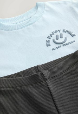 Tricou din bumbac albastru deschis cu guler cu nervuri și text brodat gri; asociat cu șorturi ribbate gri închis cu talie elastică.