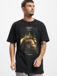 T-shirt en coton noir avec un imprimé graphique d'une figure couronnée avec des mains, fond texturé et texte blanc en bas.