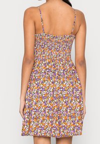 Blumenkleid mit lila, orange und weißen Mustern. Mit Spaghettiträgern und einem gerafften Mieder. Leichter Stoff, knielang.