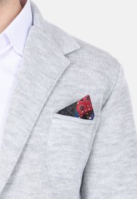 Blazer grigio a maglia con colletto a punta, caratterizzato da una tasca frontale con un fazzoletto da taschino paisley multicolore.