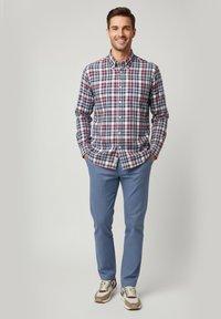 Camisa de cuadros en navy, rojo y blanco; combinada con pantalones texturizados en azul claro. Modelo lleva zapatillas con acentos.