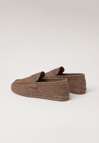 Brune ruskind derbysko med rund tå, som har en syet detalje og en vævet jute sål. Designet inkluderer en lavskåret silhuet.