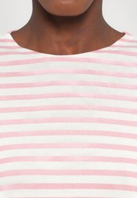 Pasiasta koszula z poziomymi różowymi i białymi paskami, wykonana z miękkiego, prążkowanego materiału, z szerokim, okrągłym dekoltem.