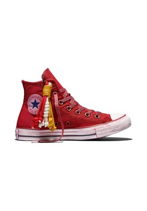 Rode hoge Converse All Star sneaker met witte zool, roze veters en kleurrijke rode, gele en witte geknoopte koorden bevestigd bij de enkel.