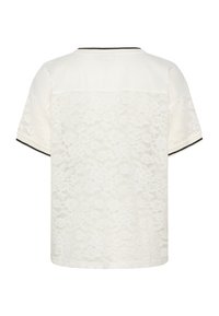 Chemise blanche à manches courtes avec motif floral en dentelle dans le dos et bordure rayée noire et blanche aux manches et au col.