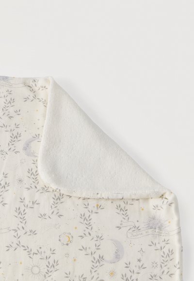 Mehak bela odeja s sivimi in zlatimi nebeškimi vzorci lune, sonca in zvezd, en kot prepognjen, da pokaže puhasto teksturirano podlogo.