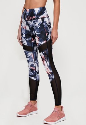 Leggings de sport taille haute présentant un motif géométrique bleu et rose, avec des panneaux en maille noire et un tissu lisse et extensible.