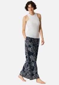 White sleeveless top and navy pants with a light geometric pattern. Pants are loose-fitting and have pockets. Soft, breathable fabric.