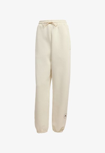 Beige sweatpants with elastic waistband and cuffs, drawstring at waist, side pockets, and small logo near bottom hem on left leg.