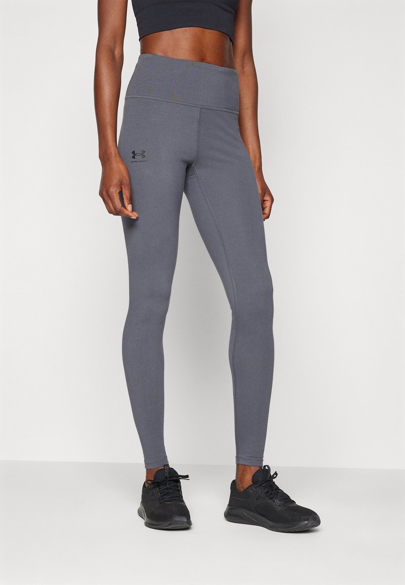 Grå treningsleggings med høy midje, laget av glatt stoff og med en subtil logo på låret. Sammen med svarte joggesko.