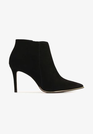 Schwarze Wildleder-High-Heel-Stiefelette mit spitzer Zehe und schlankem Absatz, dekoriert mit einer dezenten goldenen Verzierung entlang der Sohle.