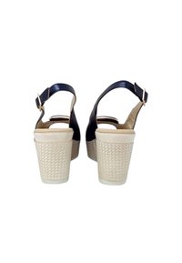 Sandali in pelle blu navy con cinturino a fibbia, dotati di un tacco platform bianco testurizzato e una suola beige liscia.