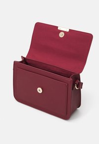 Borsa a spalla in pelle bordeaux con chiusura a scatto dorata, interno testurizzato e un ampio scomparto. Forma rettangolare con una parte frontale piatta.