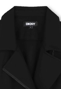 Veste noire DKNY présentant un col pointu, des détails zippés et une texture de tissu lisse. L'étiquette indique une taille 8.