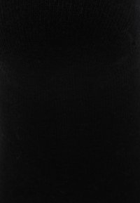 Knee-high black socks made of soft, stretchy fabric with a smooth texture and seamless design for comfort and fit.