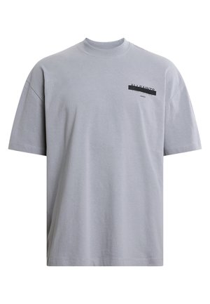 T-shirt en coton gris avec un col rond, des manches courtes, et un texte noir imprimé sur la poitrine gauche. Présente une coupe décontractée et une texture douce.