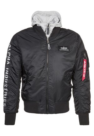 Black bomber jacket with gray hoodie lining, zipper closure, ribbed cuffs, and "ALPHA INDUSTRIES" text on the sleeve. Notable red tag detail.