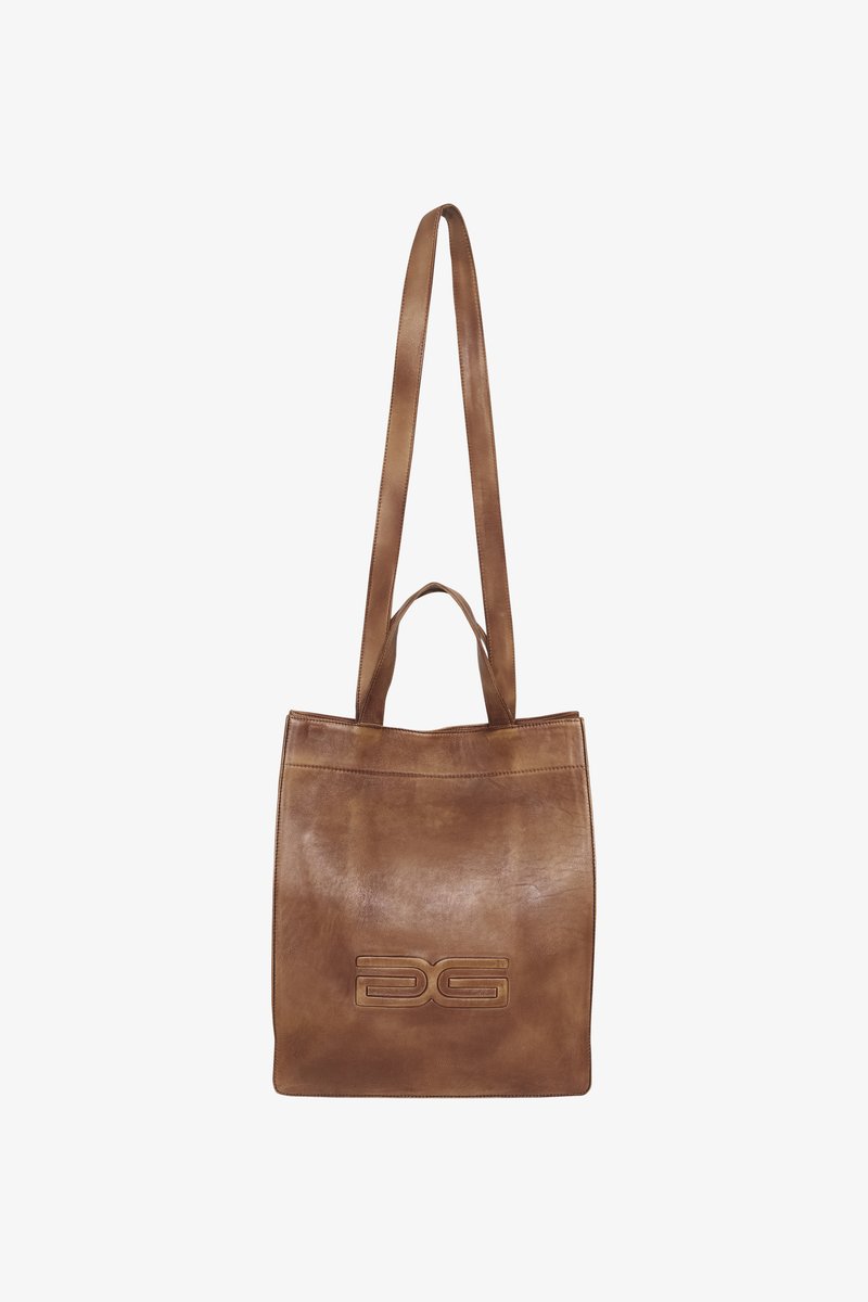 Καφέ δερμάτινη τσάντα tote με λεία υφή, διαθέτει μπροστινό λογότυπο, μακριές λαβές και απλό ορθογώνιο σχέδιο.