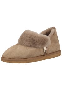 Mocassin en daim beige avec un col doux et duveteux et une semelle en caoutchouc flexible, conçu pour le confort avec des accents de couture le long du bord.