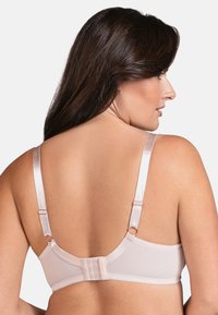 Reggiseno beige con spalline regolabili e chiusura sul retro a gancio. Tessuto liscio con una consistenza morbida. Presenta dettagli in hardware color oro rosa.