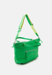 Sac à main en cuir vert avec poche avant zippée, bandoulière détachable bicolore en vert néon et jaune, et texture lisse.