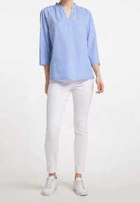 Blå och vit randig skjorta med halv-knäppning, trekvartslånga ärmar; tillsammans med vita skinny jeans och vita sneakers.