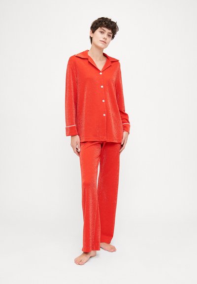 Red pajama set made of soft fabric, featuring a collared button-up top and matching flared pants with white trim and a subtle shimmer.