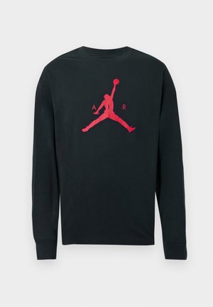Maglietta nera a maniche lunghe in cotone, con un grande logo rosso di Air Jordan che mostra la silhouette di un giocatore che salta per schiacciare un pallone da basket.