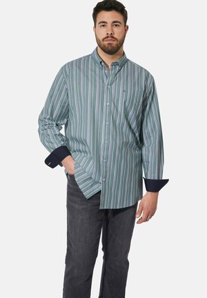 Gestreiftes Hemd in Grün mit marineblauen Manschetten. Vertikale Streifen in Weiß und Lila. Lässiger Schnitt mit abgerundetem Saum und Kragen. Getragen mit dunklen Jeans.