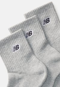 Drei Paare hellgrauer, gerippter Crew-Socken mit einem schwarz-weißen "NB"-Logo, das nahe dem oberen Bündchen gestickt ist.