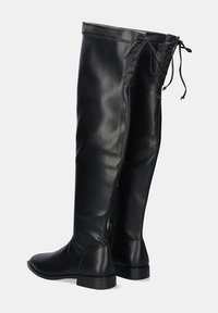 Botas negras por encima de la rodilla, hechas de cuero suave, con una cremallera trasera y detalle de cordones en la parte superior con un diseño minimalista.