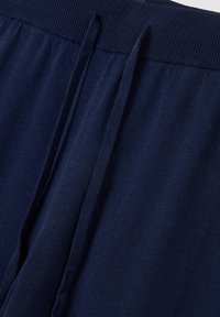 Navyblauwe sweatpants met een geribbelde tailleband, voorzien van trekkoorden en een zachte textuur. Het materiaal is lichtgewicht en comfortabel.