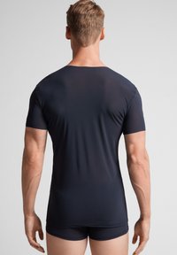 Camisa ajustada de manga corta en azul marino, fabricada con un material suave y elástico, mostrada desde la parte de atrás. Presenta un cuello redondo y costuras mínimas.