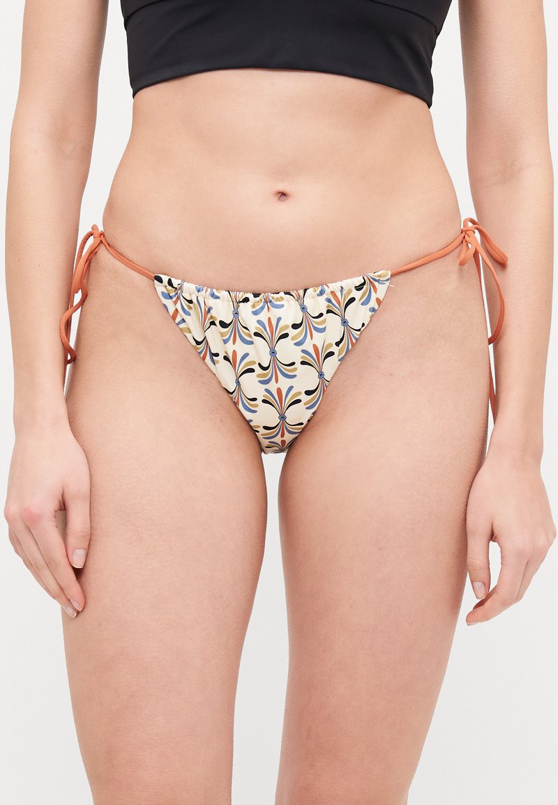 Bas de bikini à motif floral crème, avec des liens oranges sur les côtés et une taille froncée pour un ajustement réglable.