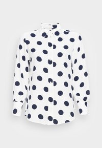 Biała koszula z długim rękawem i guzikami, w duże czarne kropki, z ostrym kołnierzykiem i zapięciem na guziki przy mankietach.