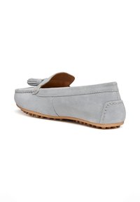 Mocassino in suede grigio chiaro con dettaglio nappine, suola in gomma color cuoio con tacchetti antiscivolo, mostrato da un angolo posteriore su sfondo bianco.