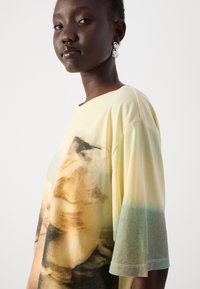 Oversized, short-sleeve T-shirt in soft cotton. Features a gradient from yellow to teal with abstract patterns and a round neckline.