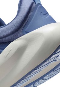 Zapatilla deportiva de color azul claro con parte superior de tela texturizada, detalles de plástico suave y una suela de goma blanca y azul duradera con un patrón de tracción.