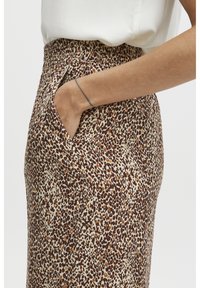Spódnica w wzór panterki z beżowym tłem i brązowymi akcentami, elastyczny pas i boczne kieszenie. Gładka tekstura z dopasowanym krojem.