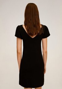 Vestido negro con escote en V en la espalda y mangas abullonadas. Diseño ajustado, hasta la rodilla, hecho de tejido suave, sin patrones ni acentos visibles.