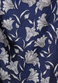 Tessuto blu navy con motivi floreali bianchi, con dettagli di linee nei petali e nelle foglie che creano un aspetto strutturato.