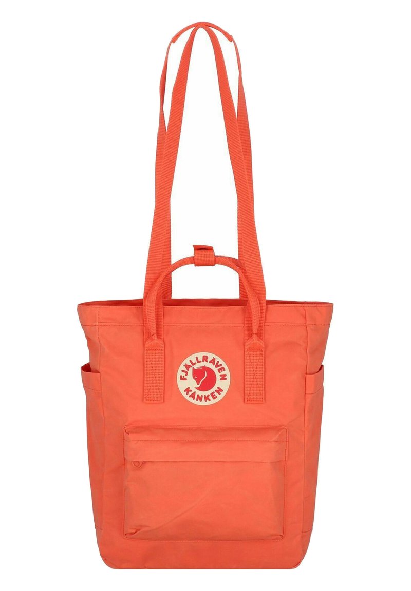 Sac tote Fjällräven Kanken orange, avec un patch logo rond, deux bretelles, une poignée supérieure et une poche zippée à l'avant.