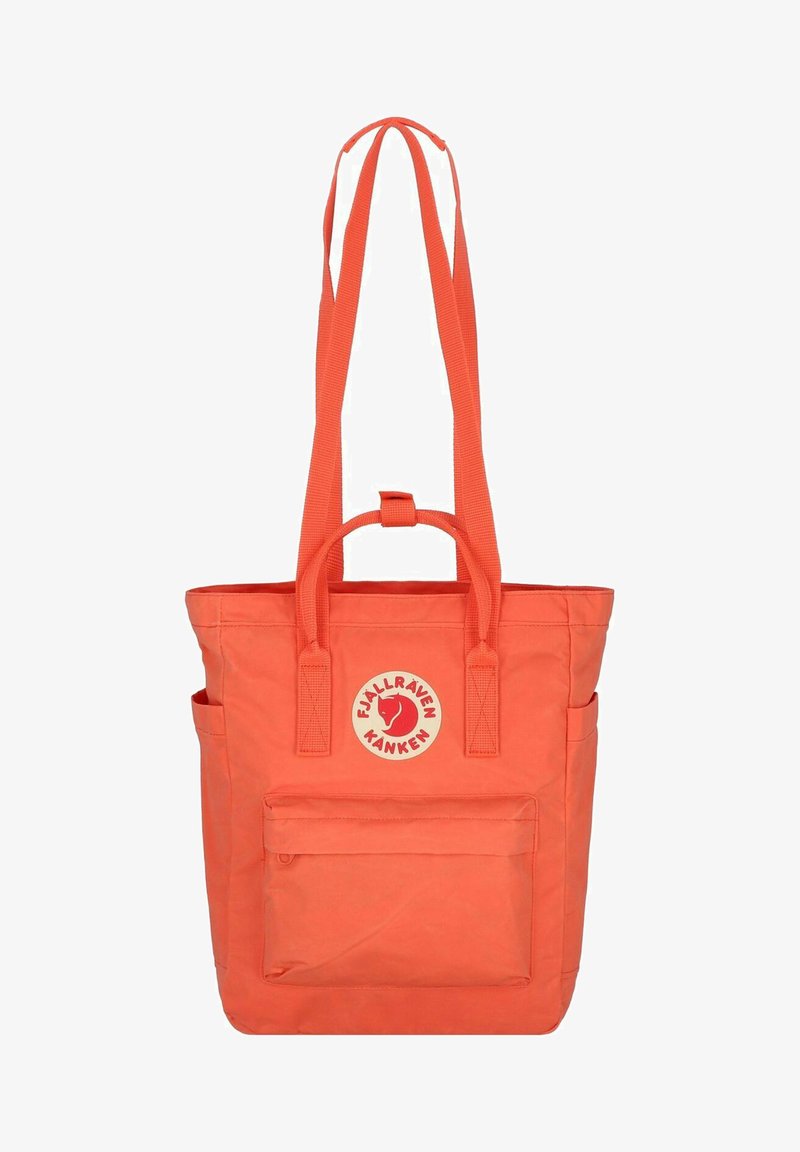 Sac tote Fjällräven Kanken orange, avec un patch logo rond, deux bretelles, une poignée supérieure et une poche zippée à l'avant.