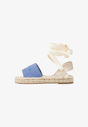 Blauwe canvas espadrille sandaal met een geweven jute zool, voorzien van een gekruiste crème strap met reliëf branding.
